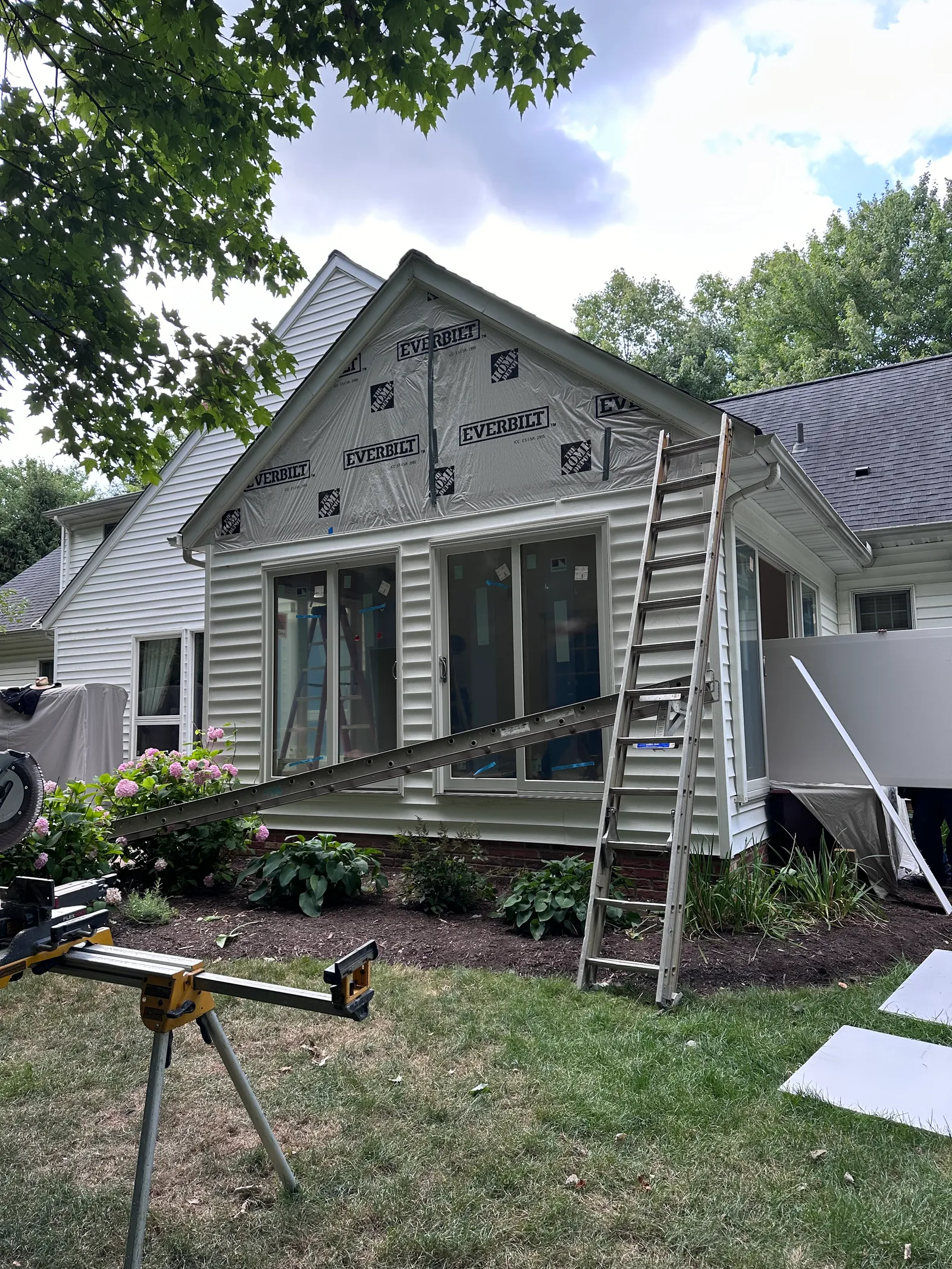 Home exterior during structural renovation with house wrap and siding work
